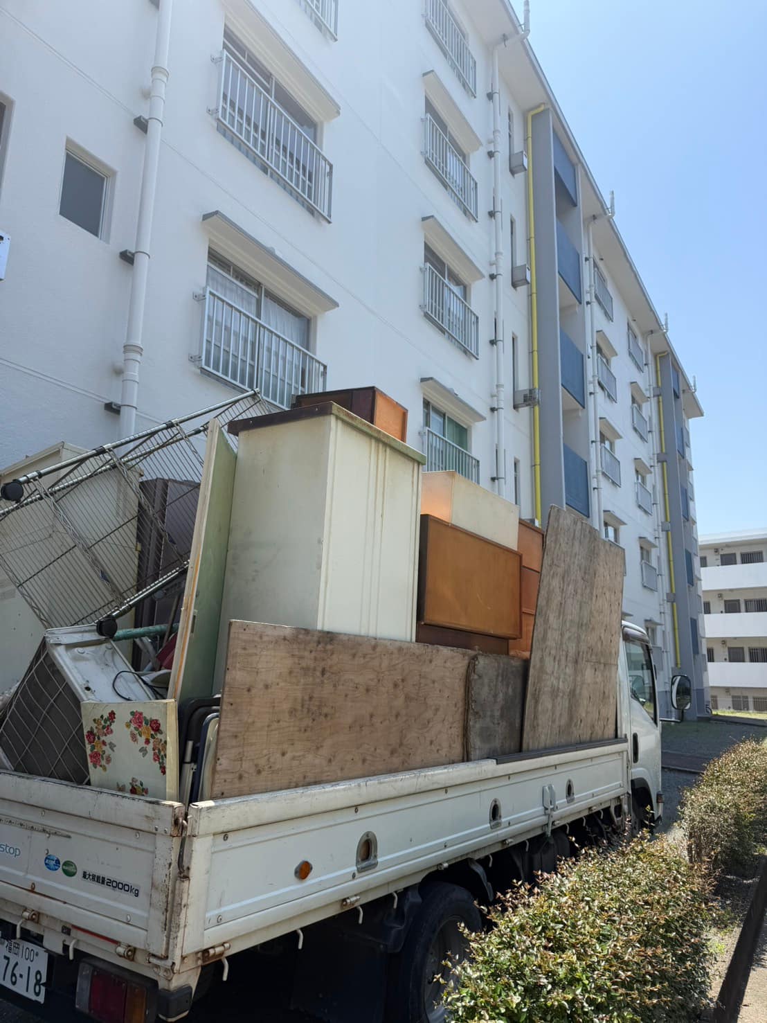 熊本県の団地3DK退去片付け事例|施設入居後の実家整理 | 九州片付け隊 熊本県内の団地退去片付けで、搬出した家具や金属ラックを積んだトラック