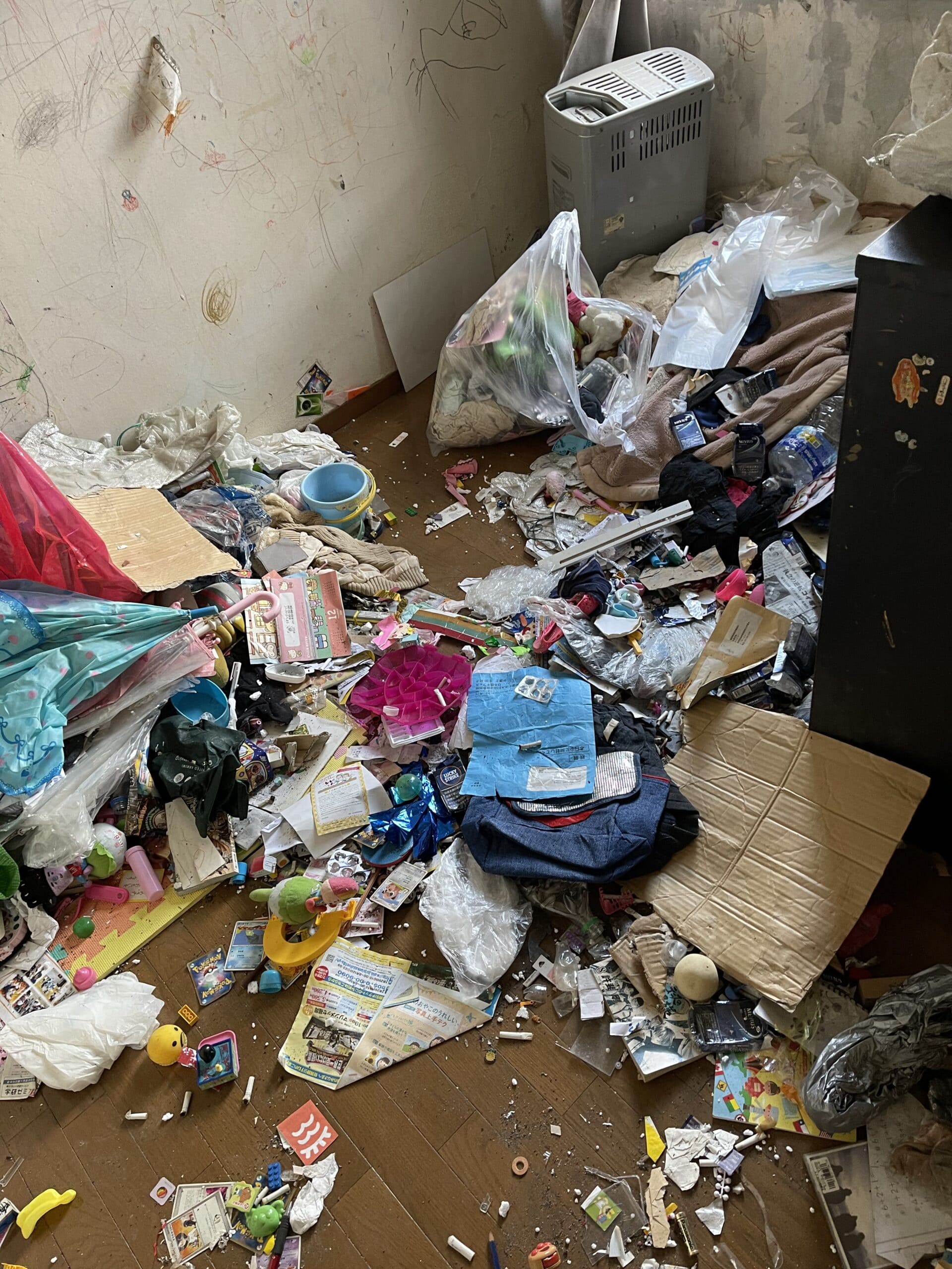 佐賀市のゴミ屋敷片付け事例|住み続ける2LDKを4名で整理 | 九州片付け隊 佐賀市のアパート2LDKの一室で、片付け前に生活用品やごみが床に混在した状態